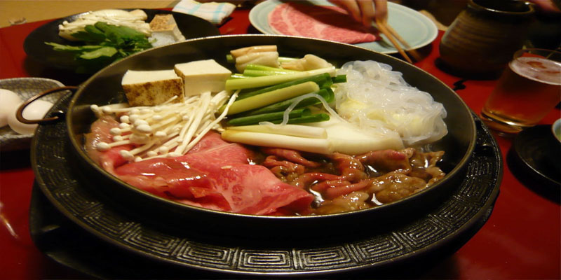SUKİYAKİ: Sukiyaki masa üzerine bir ısıtıcı, onun üzerine de kaynar su ile dolu bir tencere koyarak servis yapılan Japonya’nın diğer lezzetli yemeklerinden biridir. Malzemeler -ince kesilmiş et, çeşitli sebzeler, mantarlar ve de tofu – çiğ olarak gelir. Yiyecek kişiler bu malzemeleri masadaki kaynar suya batırıp ısıtır ve ellerinde bulunan içinde çiğ yumurta olan kâselere batırarak yerler.
